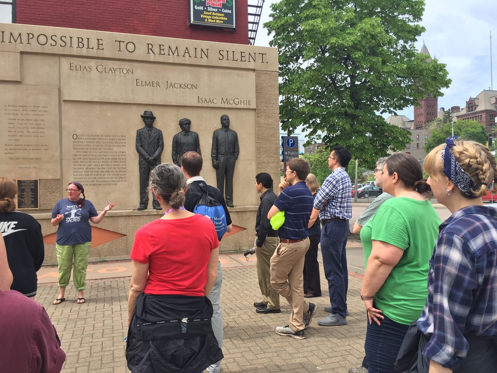 The group that included Duluth Public Library employees listen as Clayton Jackson McGhie Memorial co-founder Heidi Bakk-Hansen tells the story about the 1920 lynching during CHUM’s Expanding Horizons Tour.